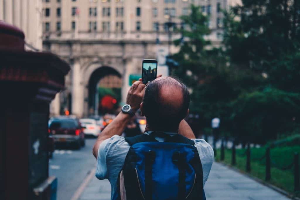 Baby boomer tourist taking photo on phone