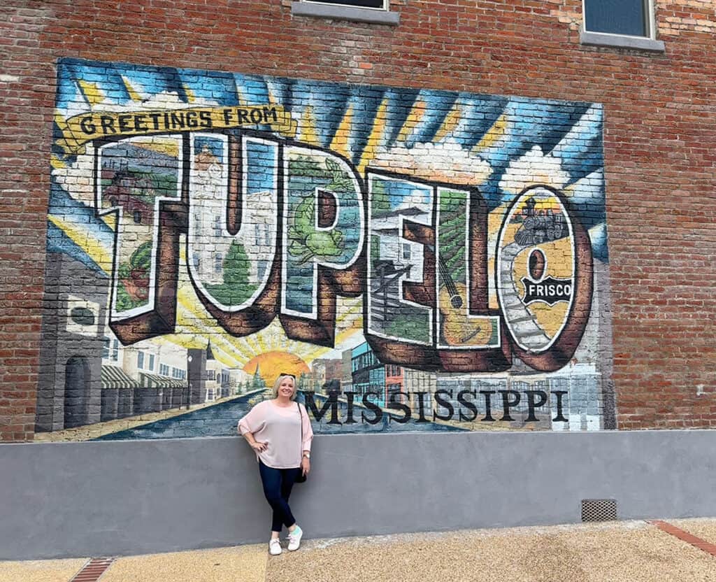 Megan standing against wall with Tupelo sign