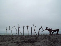 Hokitika spelled using wood sticks near a beach.