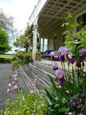 Elegant tables and chairs on the veranda of Oruawharo Homestead designed for high tea experience.